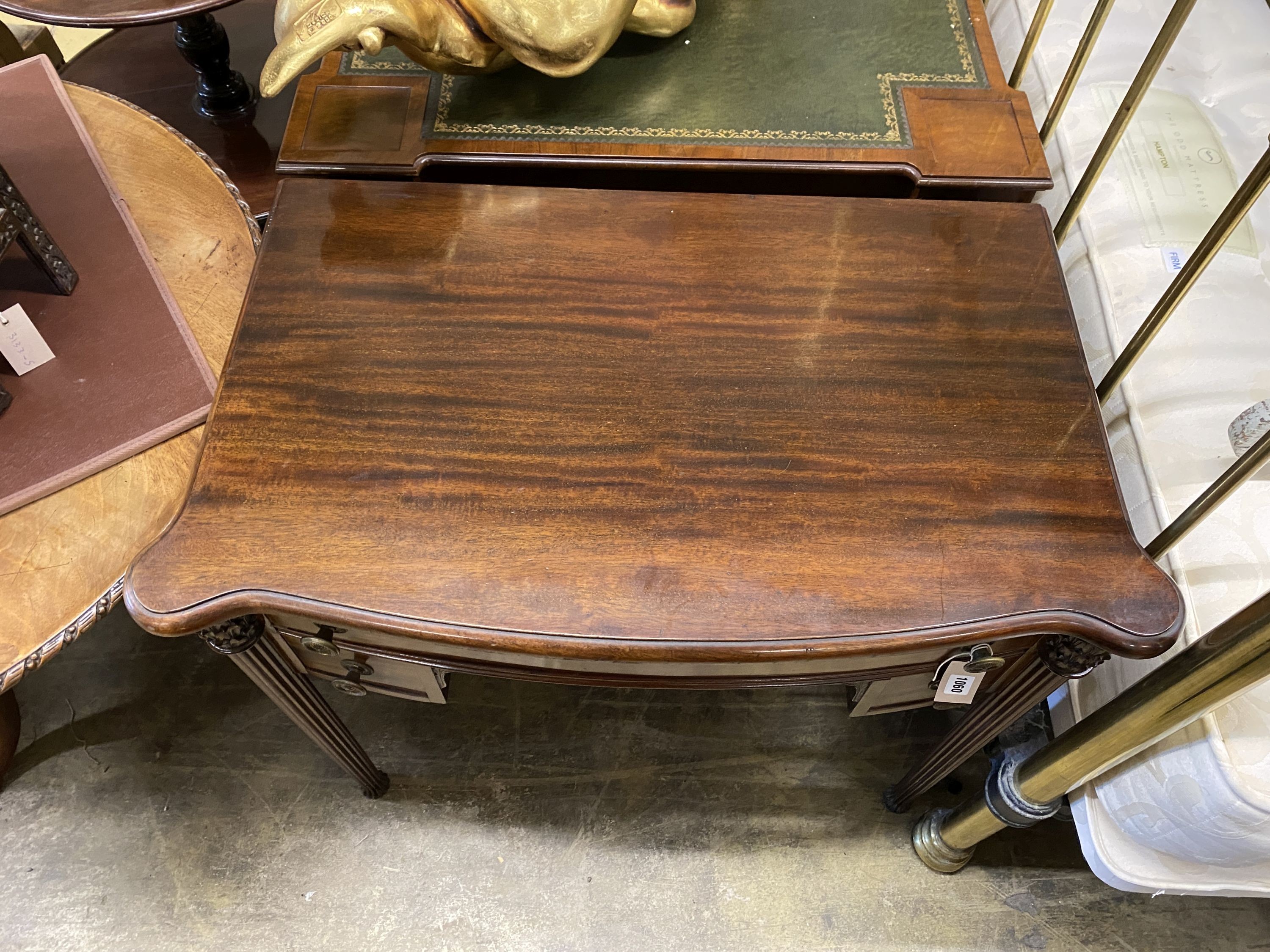 A Victorian style serpentine mahogany writing table, width 86cm, depth 51cm, height 76cm